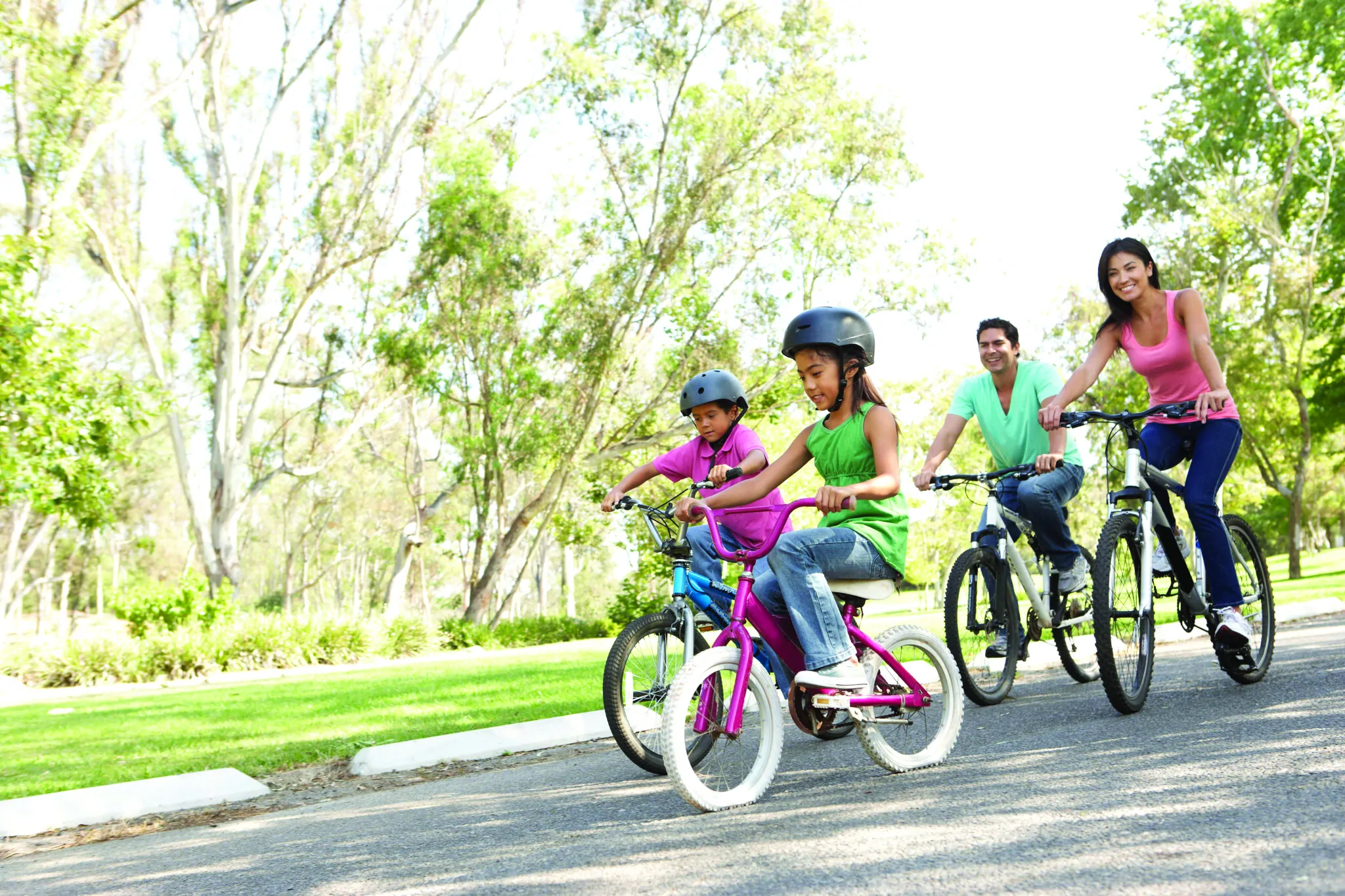 Young Family Riding Bikes In Park
